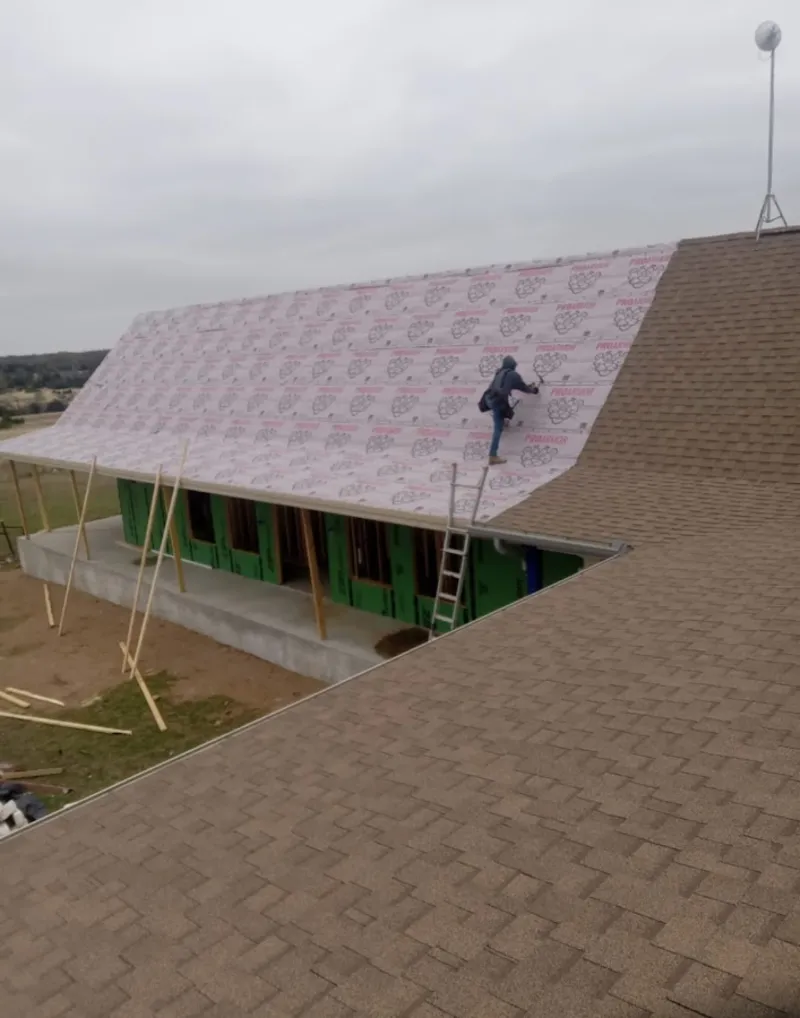 Worker preparing underlayment for a metal roof installation in Kalkaska